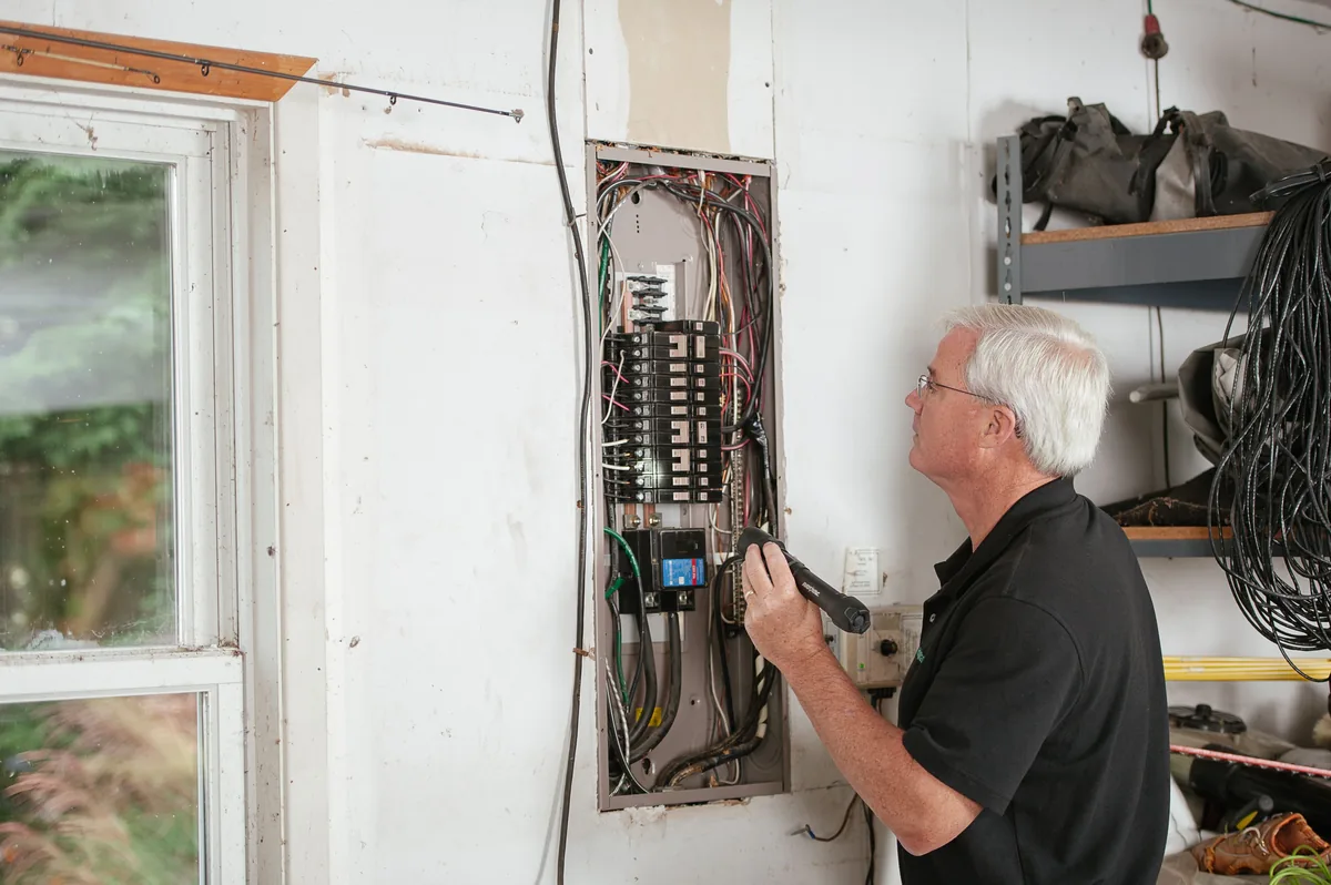 Homeowner checking a circuit breaker panel with a flashlight