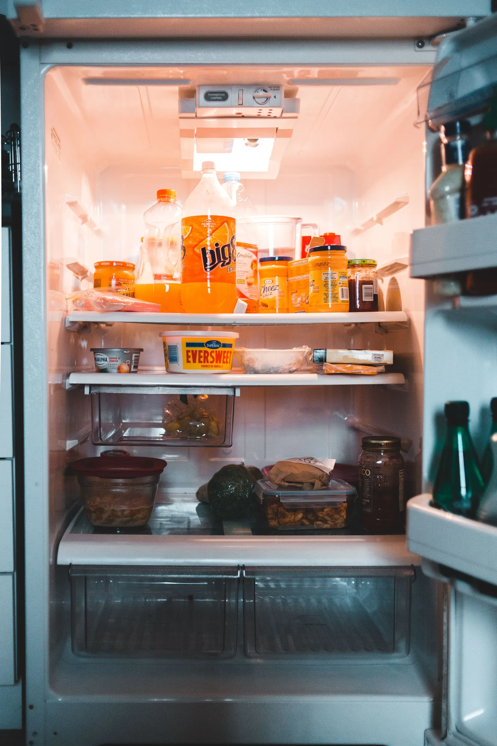 Refrigerator stocked with groceries, temperature control dial visible