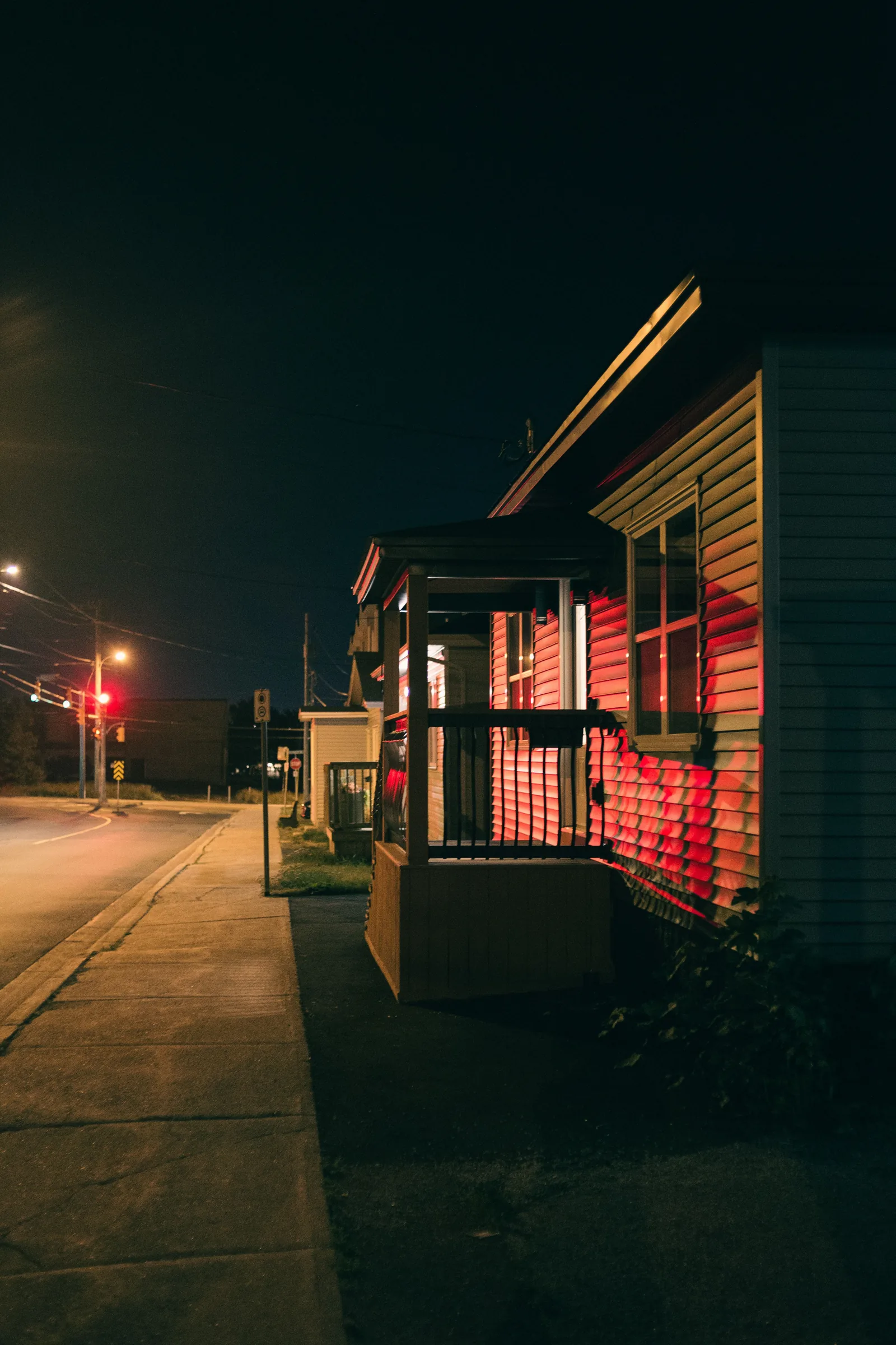Quiet suburban street at night with a house lit from within during a power outage