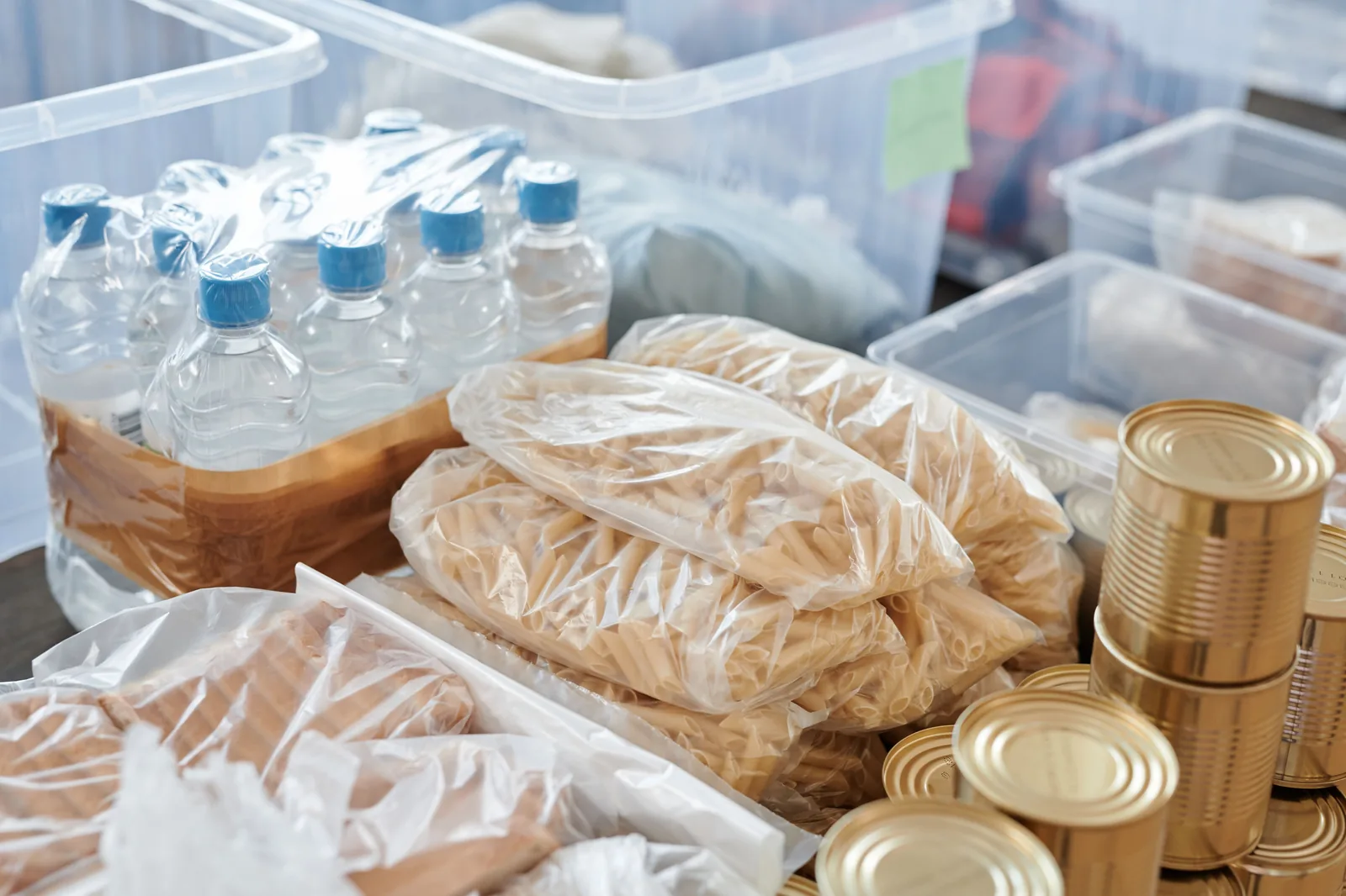 Water, pasta, and canned goods stored in bins for a power outage kit